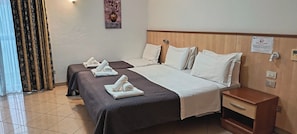 Habitación de hotel con dos camas, cabecero de madera, mesita de noche y un cartel en la pared.