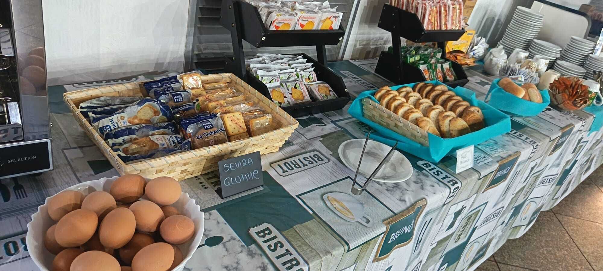 A breakfast buffet with various food items and a sign indicating gluten-free options.