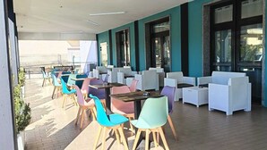 Un espace extérieur aménagé avec des tables et des chaises, une poubelle et une vue sur la rue.