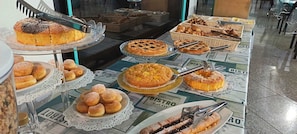 A buffet table with various baked goods, including pies, cakes, and pastries.