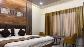 Ein Hotelzimmer mit einem Bett, einem kleinen Tisch, zwei Stühlen und einem großen Fenster mit Vorhängen.