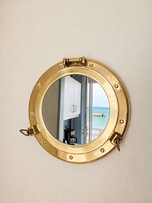 Un miroir rond, avec un cadre en laiton et un loquet articulé sur le côté gauche.