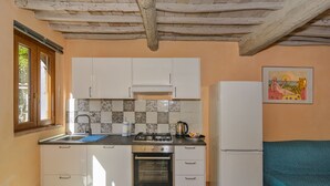 Una cocina compacta con armarios blancos, horno empotrado, estufa a gas y refrigerador.