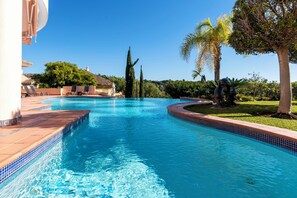 A swimming pool with a tiled edge, surrounded by lounge chairs and a statue. - Luxury Villa Robledal in Marbella by Mabiente Properties (Marbella)