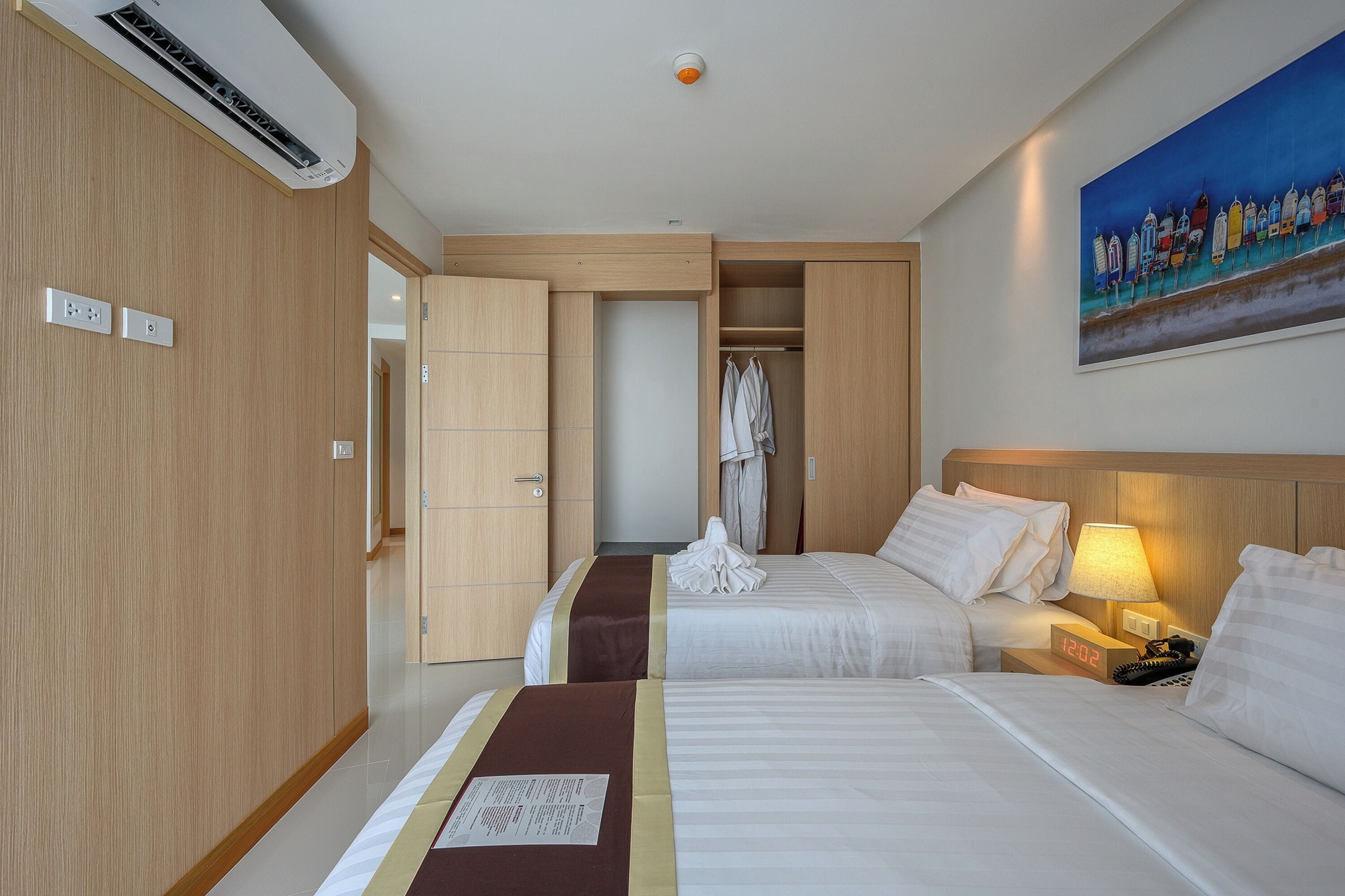 A hotel room with two beds, a wardrobe, a painting, and a clock.