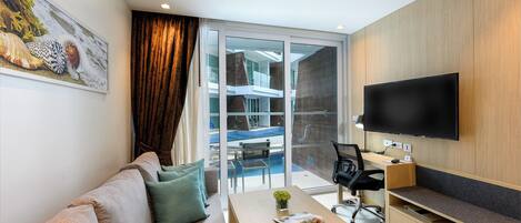 Una sala de estar moderna con sofá, mesa de centro, televisor y vistas a un balcón con mobiliario exterior.