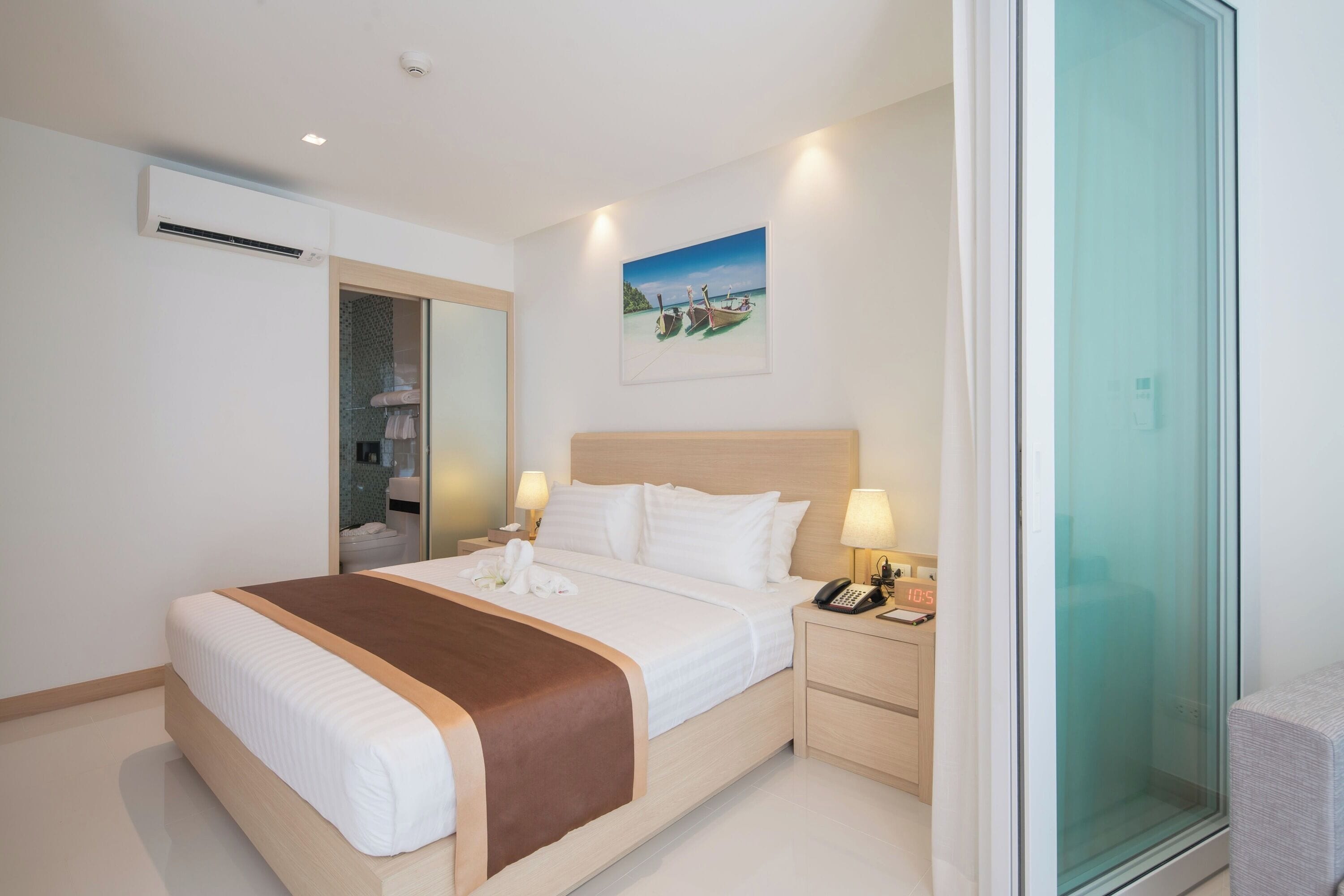 A hotel room with a bed, bedside tables, a mirror, and a painting on the wall.