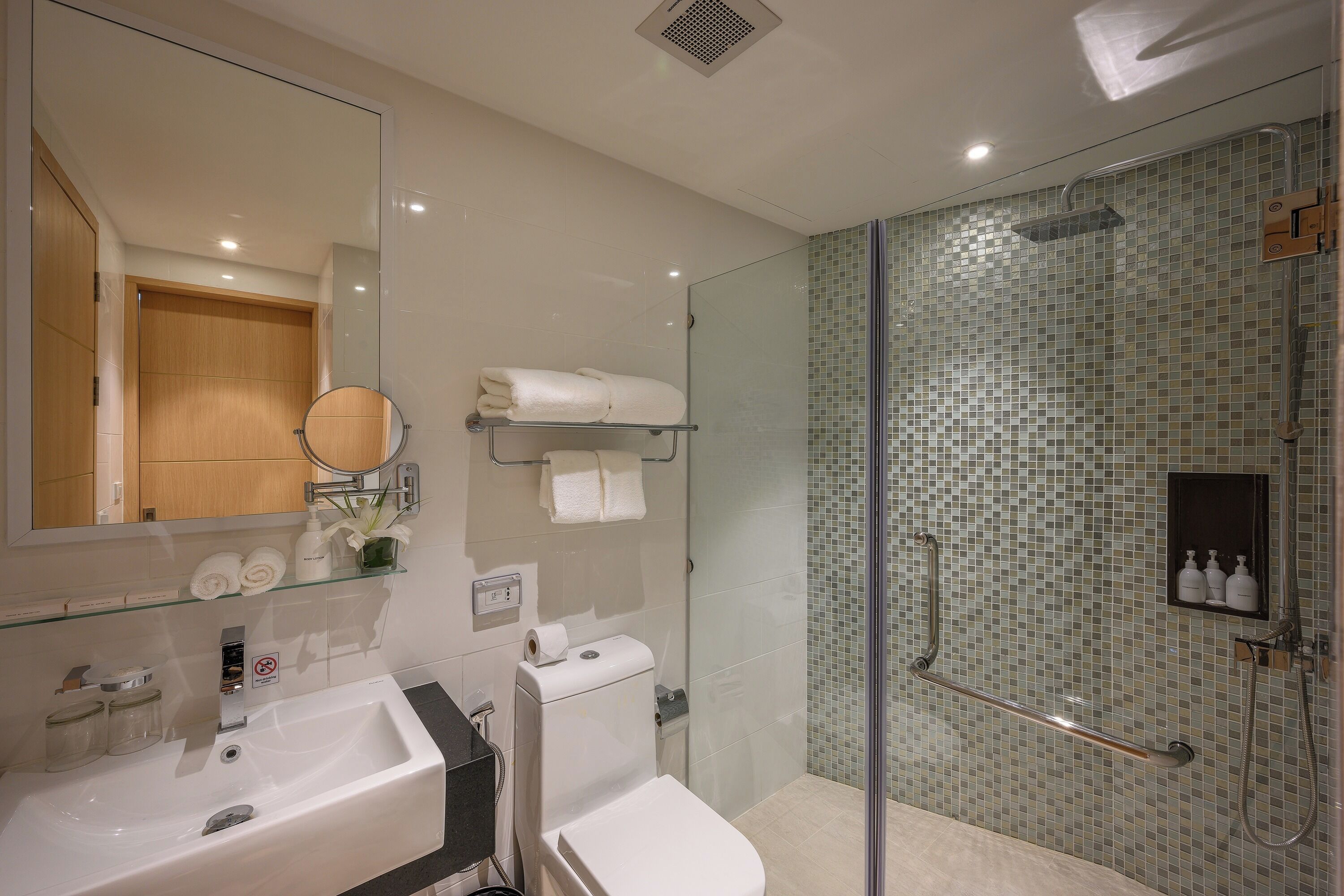 Un baño moderno con cabina de ducha de vidrio, lavamanos y retrete.