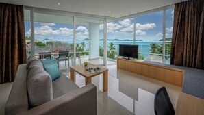 Una sala de estar moderna con un sofá, una mesa de centro y un televisor, con vistas a un paisaje marino.