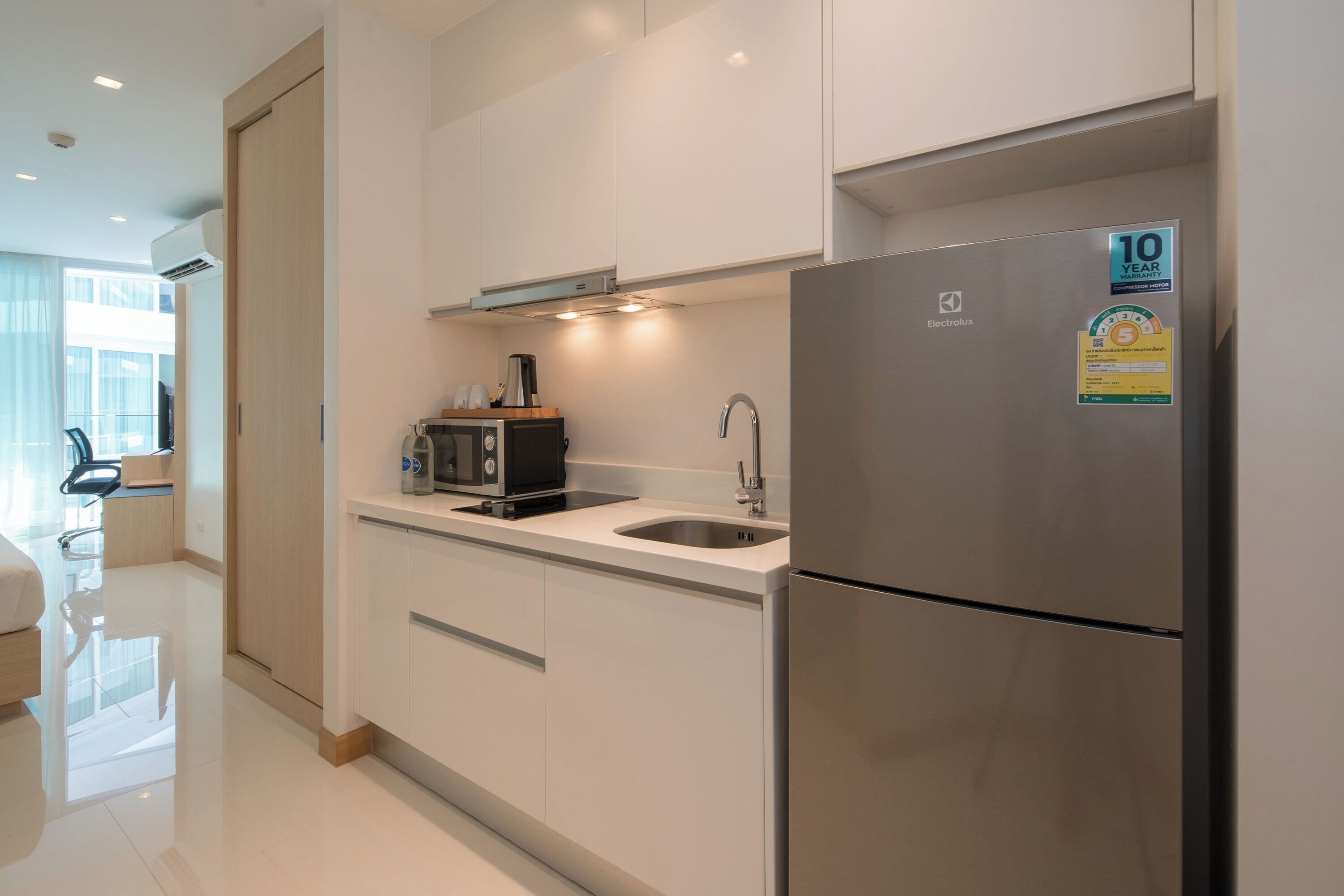 A modern kitchen with white cabinets, a stainless steel refrigerator, and a built-in microwave.