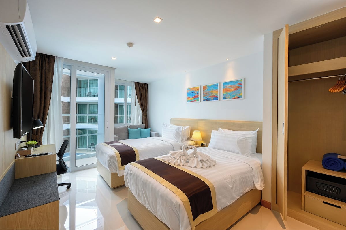 A hotel room with two beds, a TV, a desk, and a wardrobe.