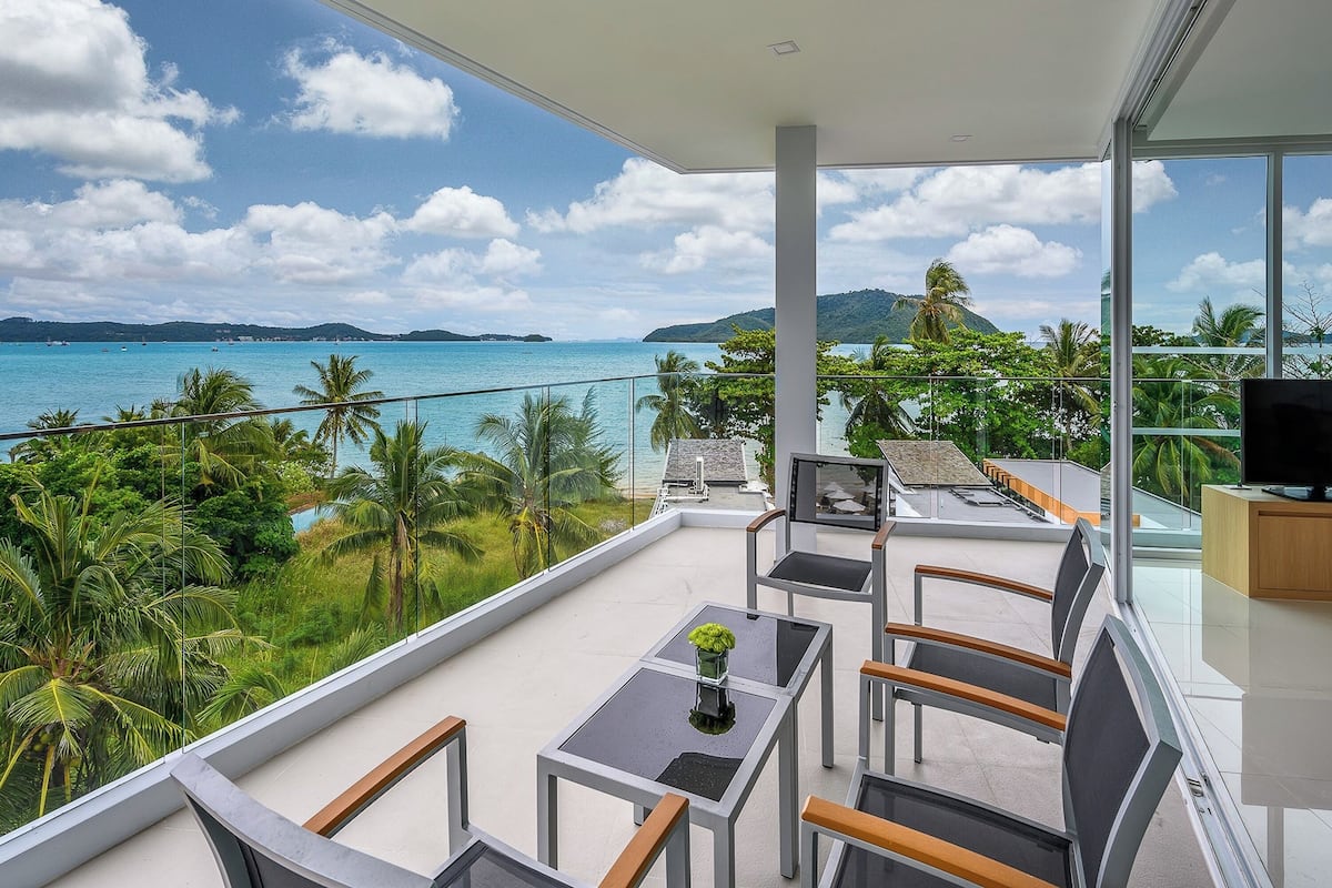 A balcony with a glass railing, a table with chairs, and a TV.