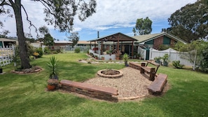 A well-maintained backyard with a barbecue area, a wooden deck, and a variety of potted plants.