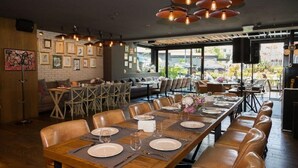 A restaurant with a long wooden table set for a meal, surrounded by leather booths. - Hotel Emirates (Sofia)
