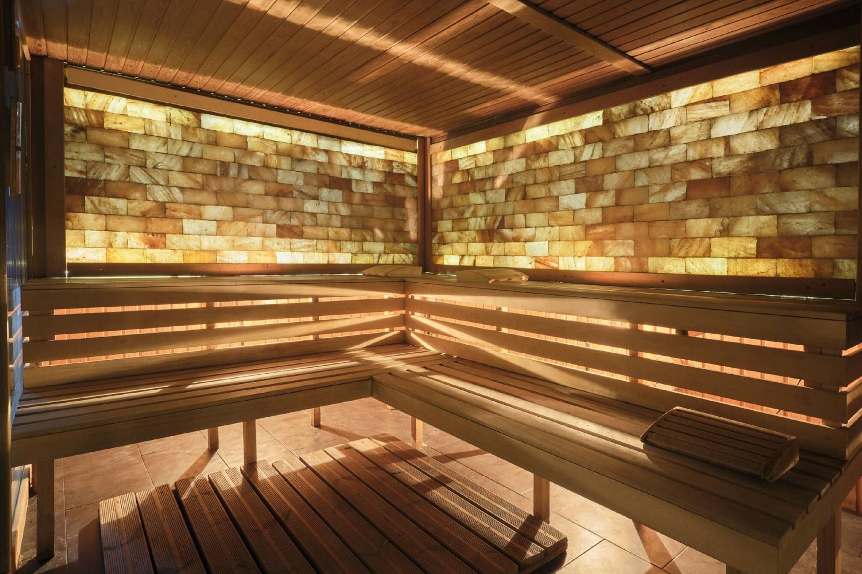 Un sauna avec des bancs en bois et un mur en pierre.