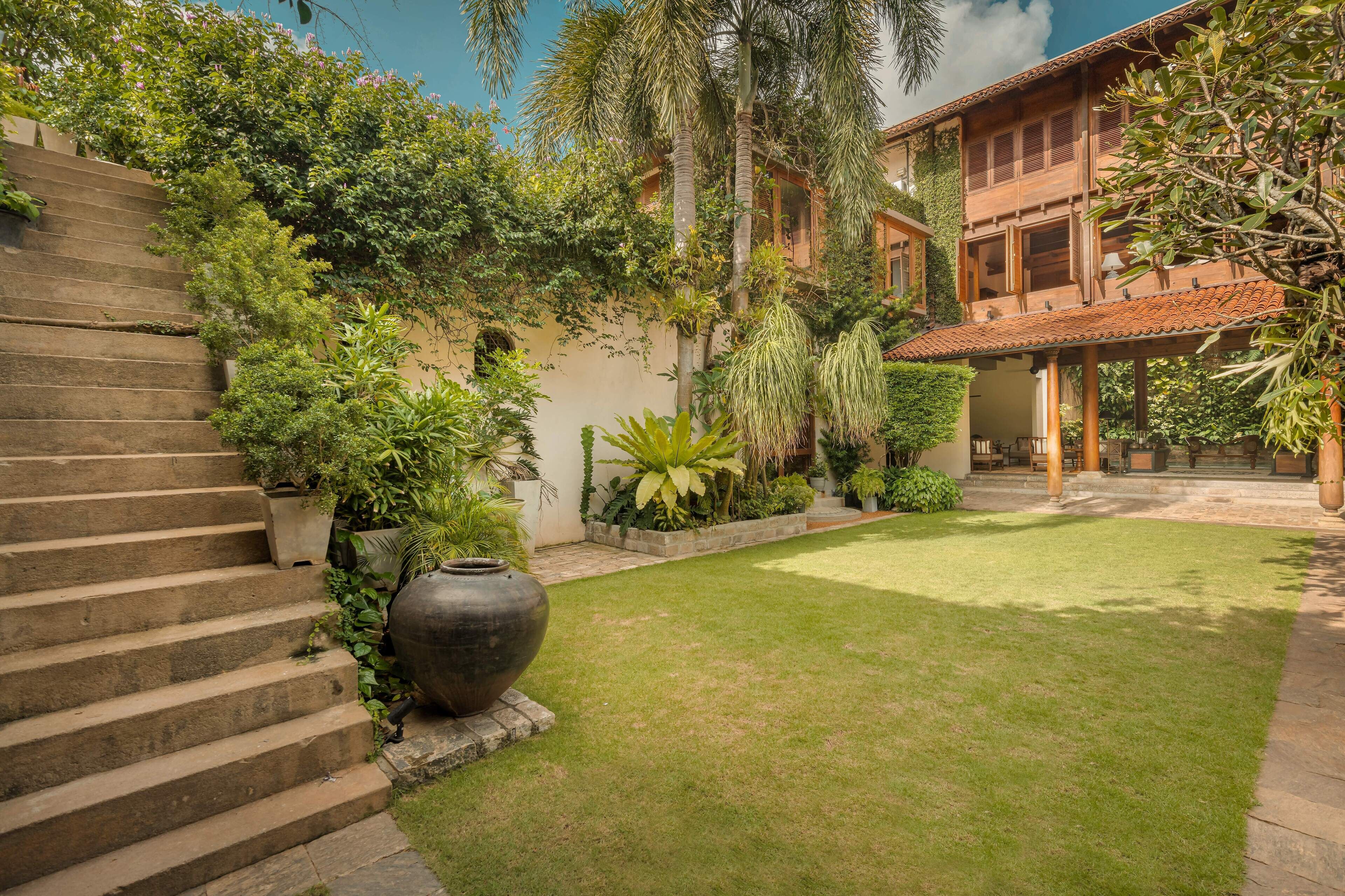 A courtyard with a staircase, a large planter, and a building with a tiled roof.