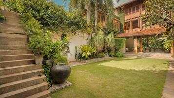 A courtyard with a staircase, a large planter, and a building with a tiled roof.