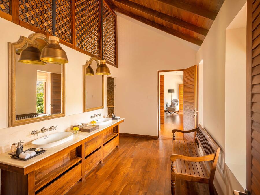 A bathroom with wooden floors, a bench, and a large mirror.