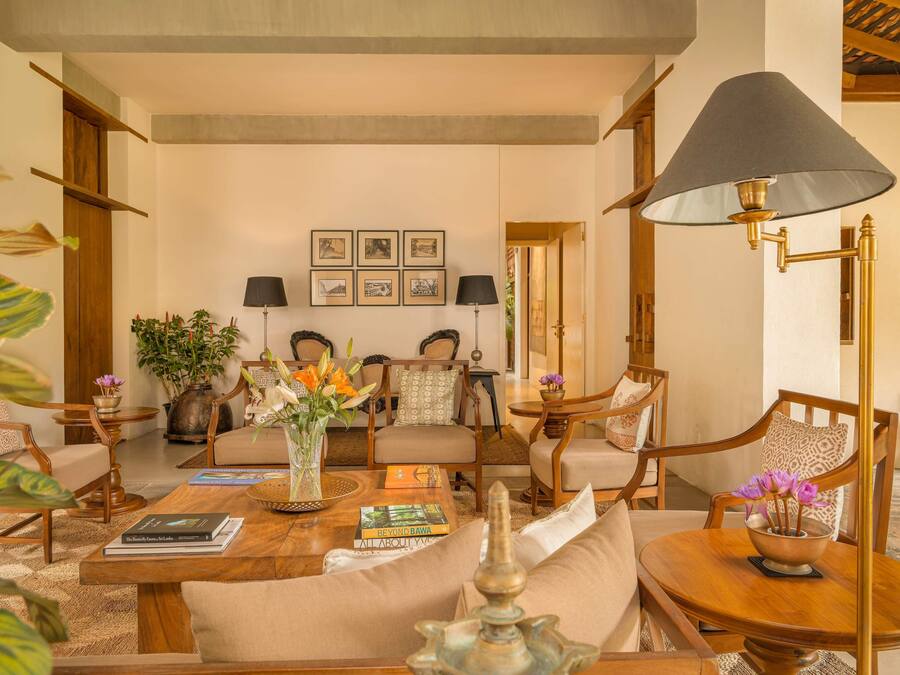 Un salon bien éclairé, avec un canapé, une table basse sur laquelle sont posés des livres et une lampe.