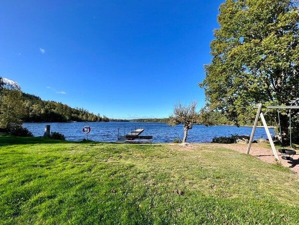 Une zone herbeuse avec un quai et une balançoire près d’un lac.