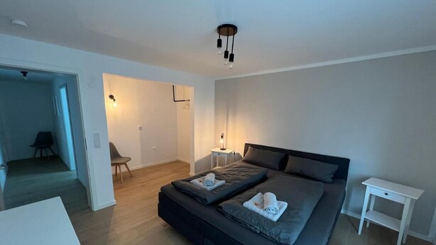 A modern bedroom with a large bed, bedside tables, and a small seating area. - Vacation apartment Kurpark Brilon on the Rothaarsteig Start (Brilon)