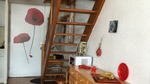 Ein Zimmer mit einem Schlafplatz in einer Holzboden-Loft, einer Küchenzeile und einer Tür mit Leinweberei-Motiven.