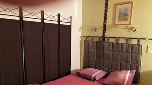 Ein Schlafzimmer mit einem Bett, einem Kopfteil, einem Kleiderschrank und einem an der Wand hängenden Bild.