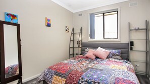 Relax in this serene bedroom with a large bed and a window offering a view of the outside.