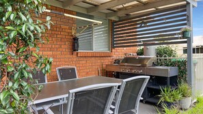 Enjoy al fresco dining and relaxation in this outdoor patio area with a grill station, table, and comfortable seating.