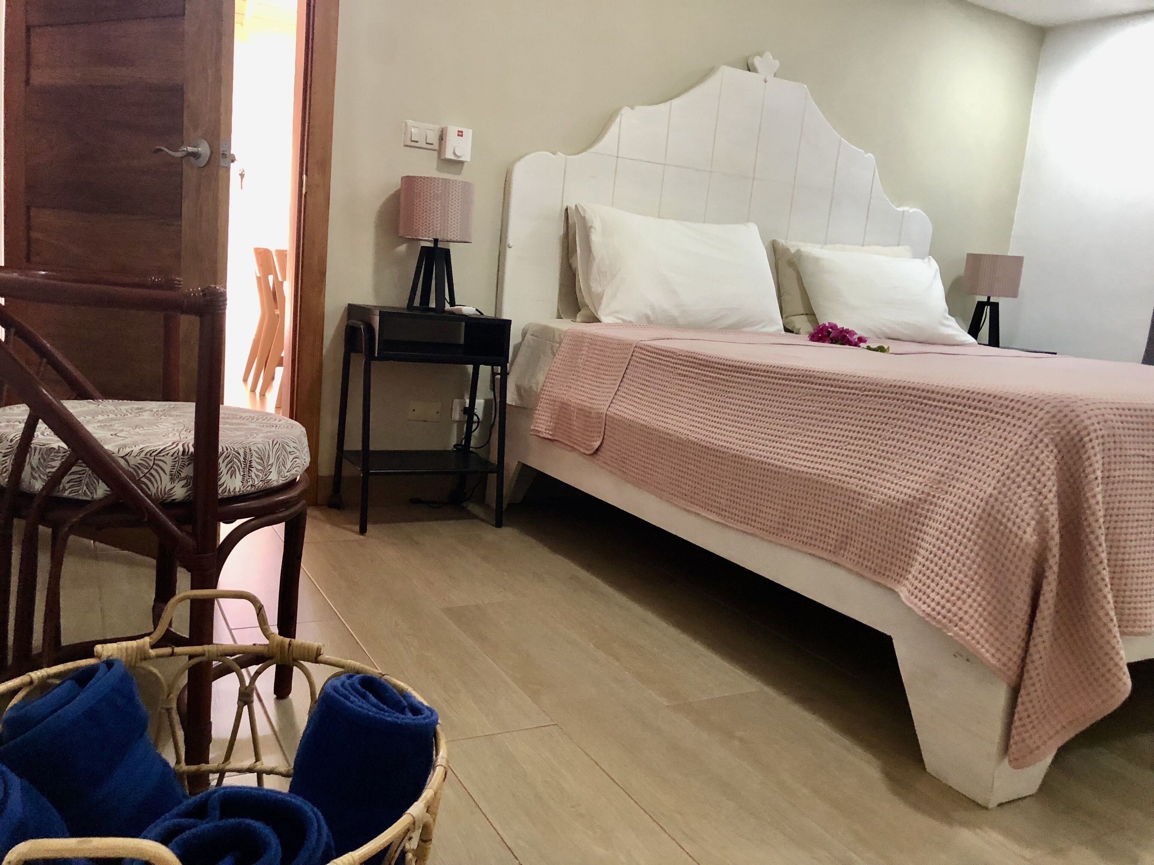 A bedroom with a bed, bedside tables, a chair, and a basket.