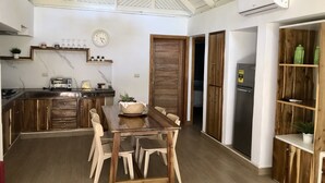 A spacious kitchen with a wooden dining table, white chairs, and a built-in stove. - ON THE Cliff IN THE Caribbean SEA - Villa Ilaria (Boca Chica)