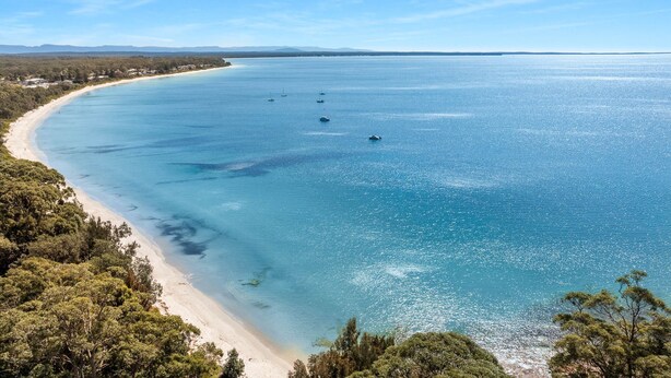Un paysage côtier avec une plage de sable et des eaux d’un bleu limpide.