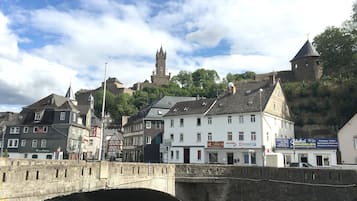 Eine historische Stadt mit einer Brücke, Gebäuden und einer Burg im Hintergrund.