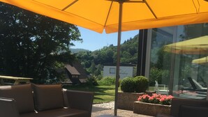 An outdoor seating area with a yellow umbrella, a sofa, and a table. - Hotel Am Fang (Bad Laasphe)