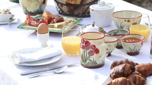 A breakfast table with croissants, bread, eggs, and fruit.