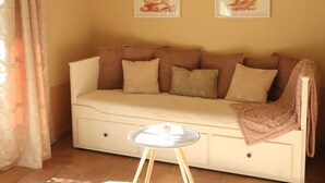 A beige sofa with multiple cushions, a small round table, and two framed artworks on the wall.