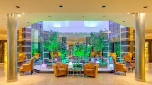 A lobby with a glass enclosure, two sofas, and a small table. - Grand Hotel Sveti Vlas (Sveti Vlas)