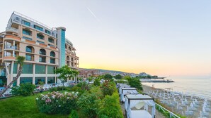 A hotel with multiple floors, outdoor seating by the sea, and a garden area with flowers. - Grand Hotel Sveti Vlas (Sveti Vlas)