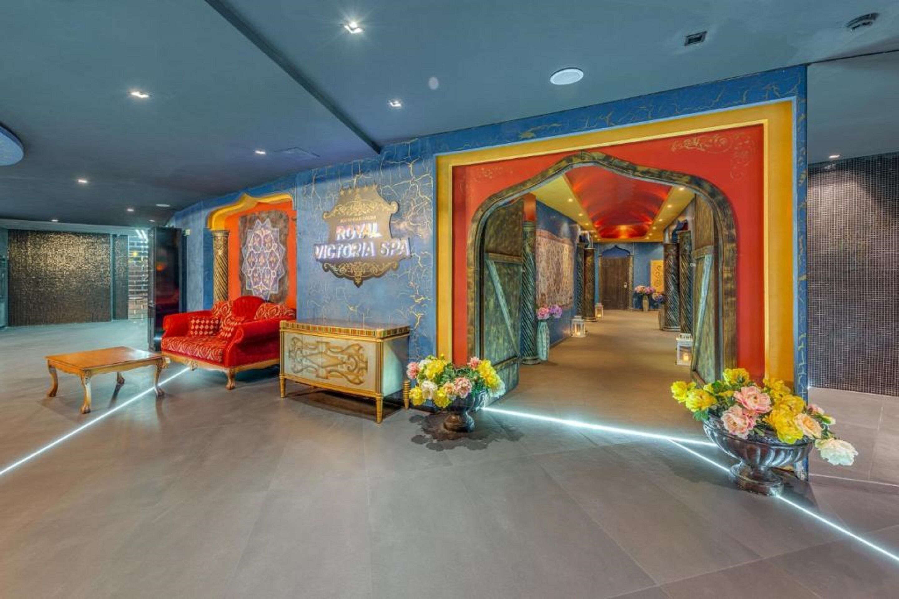A lobby with a red sofa, a gold console table, and a sign reading "ROYAL VICTORIA SPA".