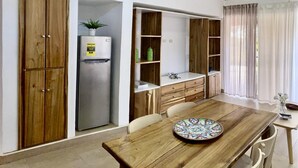 A kitchen with wooden cabinets, a refrigerator, and a dining table with chairs.