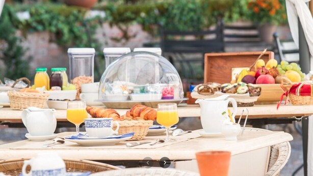 Ein Frühstück im Freien mit verschiedenen Speisen, darunter Obst, Backwaren und Getränke.