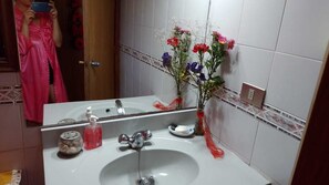 Bathroom features a sink, mirror, and two vases with flowers.
