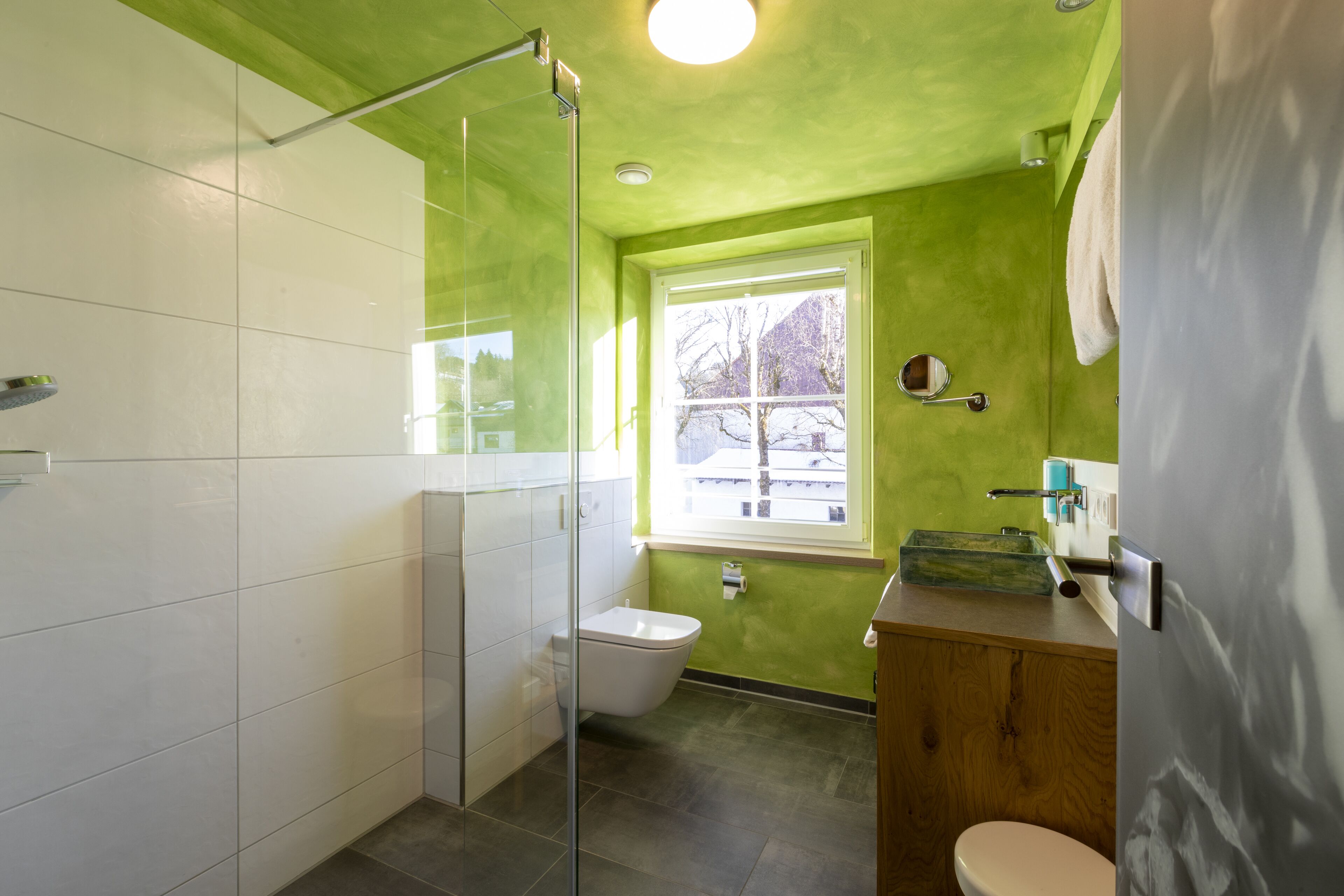 Un baño con cabina de ducha de vidrio, inodoro y lavabo con tocador de madera.
