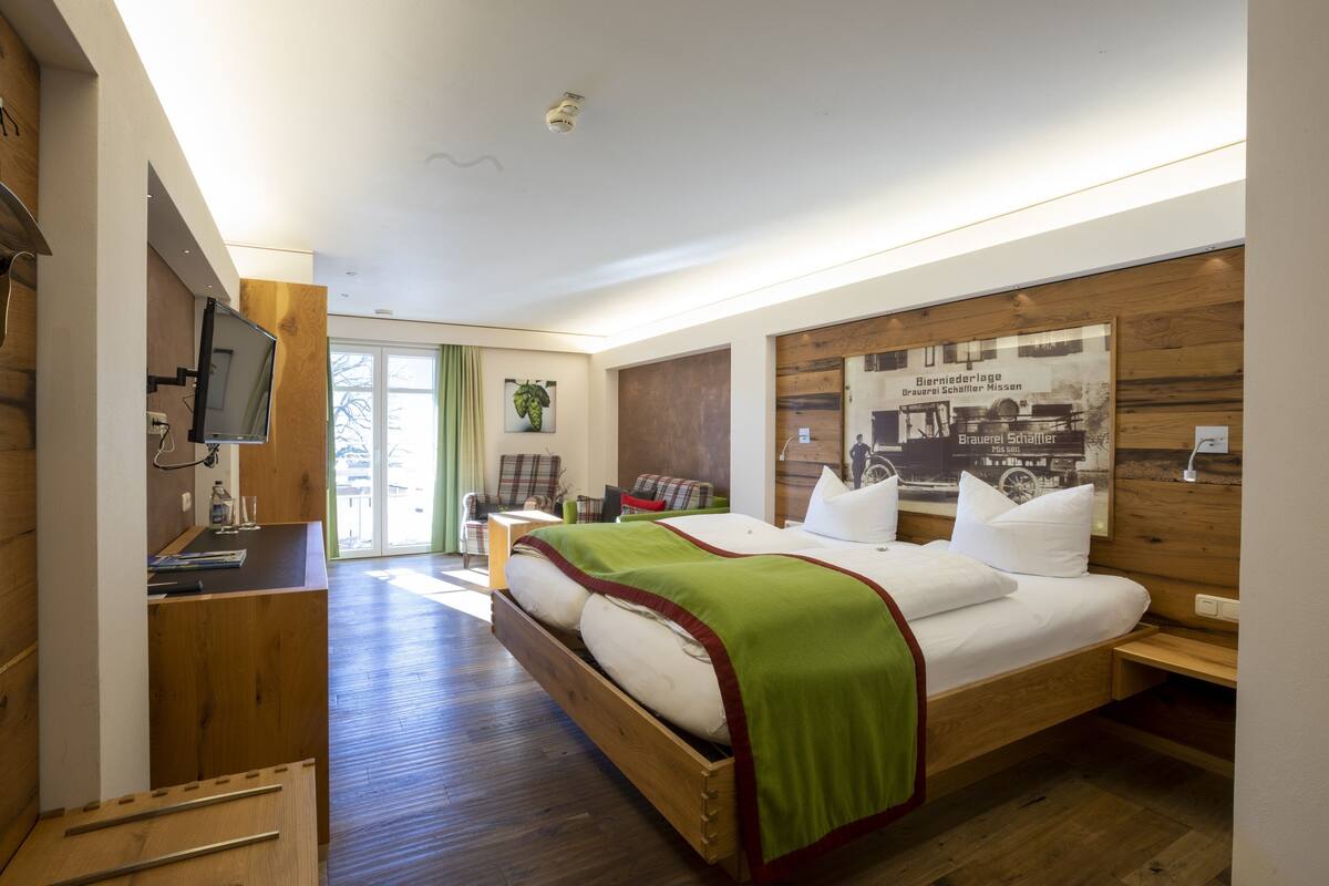 Ein modernes Hotelzimmer mit einem hölzernen Bett, einem Schreibtisch und einem Fernseher.
