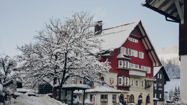 A traditional building with a red facade, multiple windows, and a snow-covered roof. - Brauereigasthof & Hotel Schäffler (Missen-Wilhams)