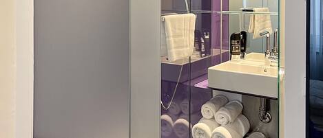 Un baño moderno con separador de vidrio, un lavamanos y un espejo.