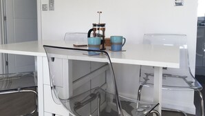 Una cocina moderna con encimera blanca, una cafetera y dos tazas azules.