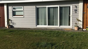 Una casa de un piso con fachada gris, una puerta principal, un gran ventanal corredizo, una ventana pequeña y un buzón.