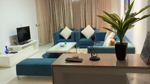 Un salon moderne avec un canapé, une table basse, un téléviseur et une plante.