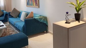 Un salon moderne avec un canapé bleu, une table basse et une plante en pot.